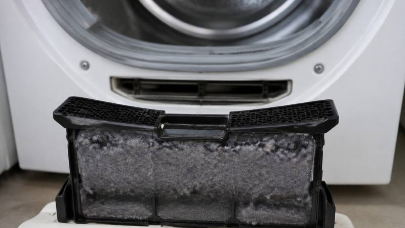 Filtre à peluches retiré d’un sèche-linge avant son nettoyage